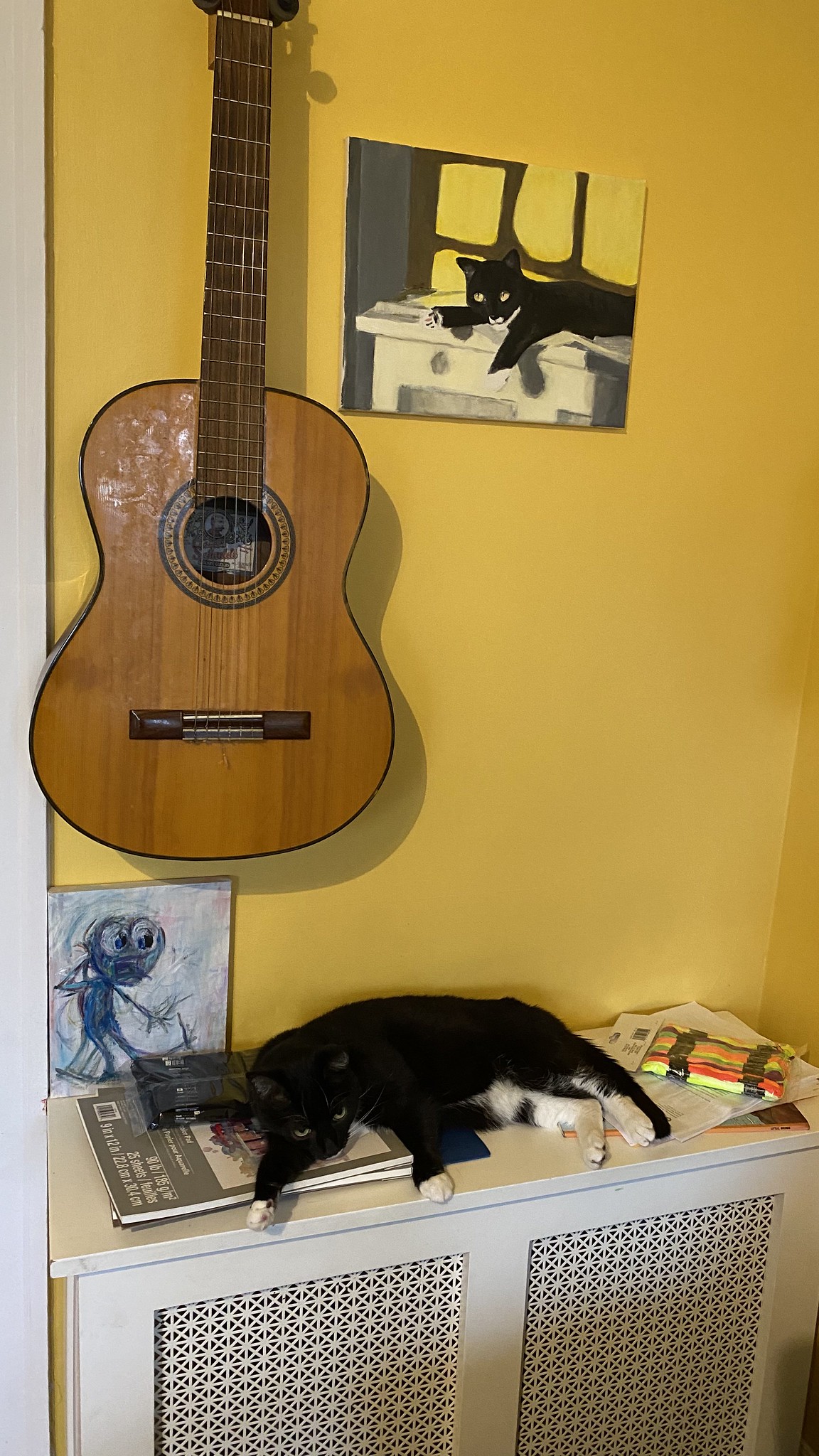 Wily on a radiator next to a painting of that same thing